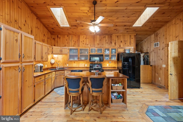 kitchen featuring a center island, wooden ceiling, a skylight, and black appliances