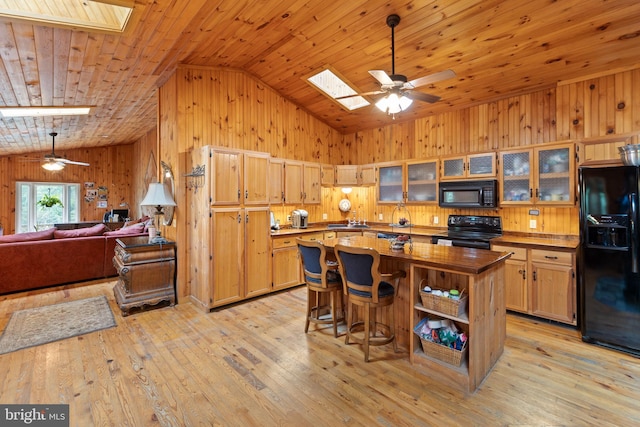 kitchen with a kitchen island, vaulted ceiling with skylight, light hardwood / wood-style floors, black appliances, and wooden ceiling