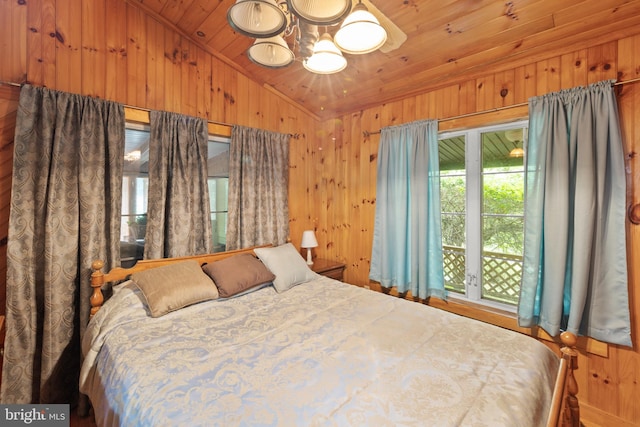 bedroom with lofted ceiling, wooden walls, an inviting chandelier, and wood ceiling