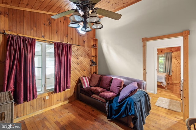 living room with hardwood / wood-style floors, wooden ceiling, ceiling fan, and wood walls