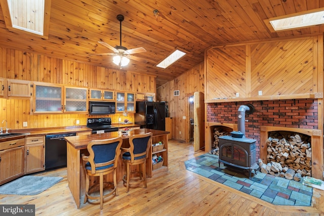 kitchen featuring lofted ceiling with skylight, sink, wood ceiling, light hardwood / wood-style flooring, and black appliances