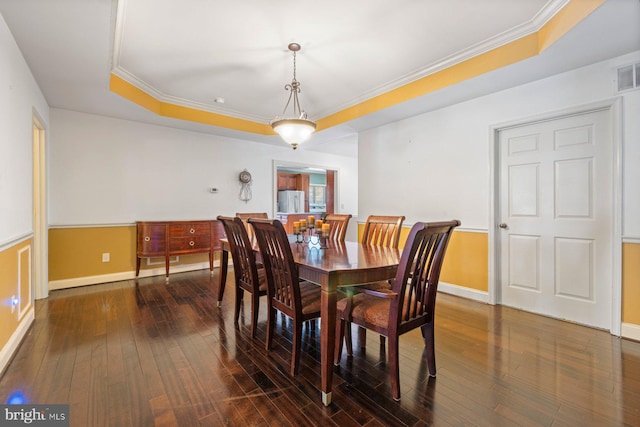 dining room featuring crown molding, dark wood-type flooring, and a tray ceiling