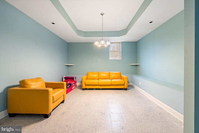 sitting room featuring a raised ceiling and a chandelier