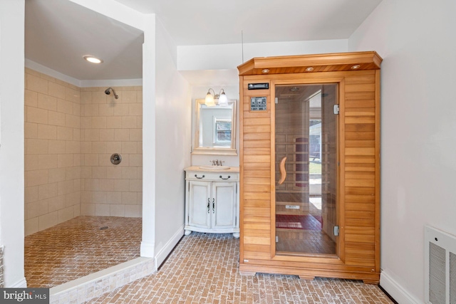 bathroom featuring vanity, a healthy amount of sunlight, and tiled shower