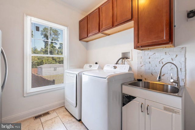 laundry area with cabinets, separate washer and dryer, light tile patterned floors, ornamental molding, and sink