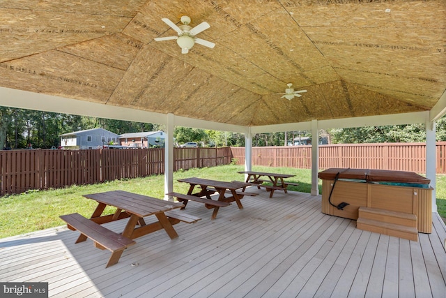 wooden deck featuring a yard, ceiling fan, and a hot tub