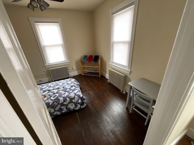 bedroom with ceiling fan, dark hardwood / wood-style flooring, and radiator