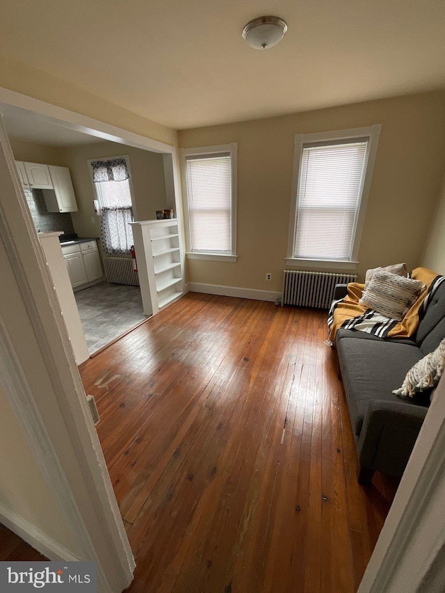 unfurnished living room with radiator heating unit, wood-type flooring, and plenty of natural light