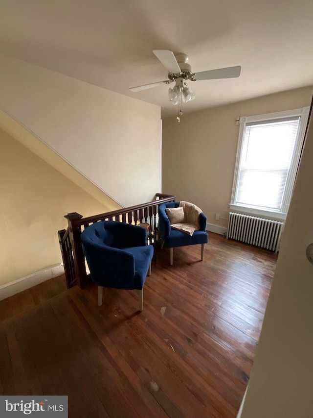 living area with ceiling fan, dark hardwood / wood-style flooring, and radiator heating unit