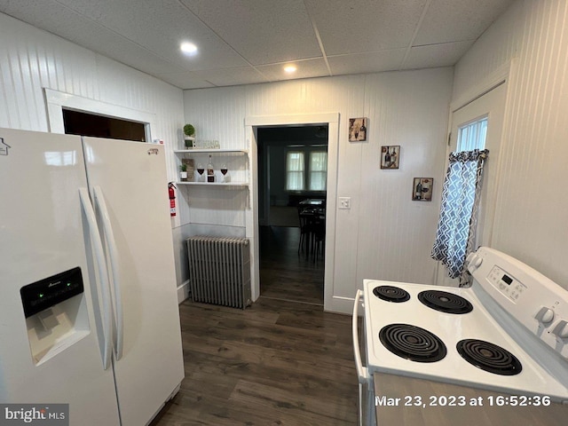 kitchen with dark hardwood / wood-style flooring, a paneled ceiling, white appliances, wooden walls, and radiator heating unit