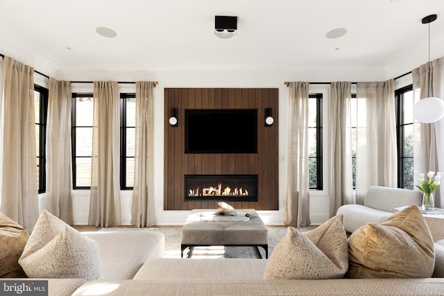 living room with a large fireplace, crown molding, and light hardwood / wood-style flooring