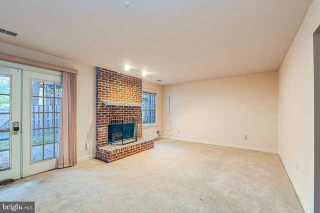 unfurnished living room featuring french doors, a fireplace, and light carpet