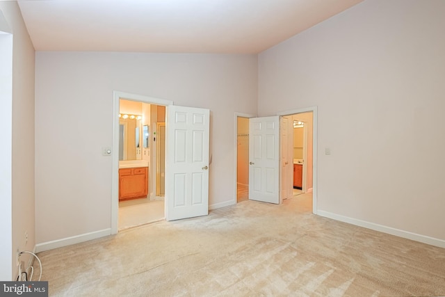 unfurnished bedroom featuring light carpet, connected bathroom, and high vaulted ceiling