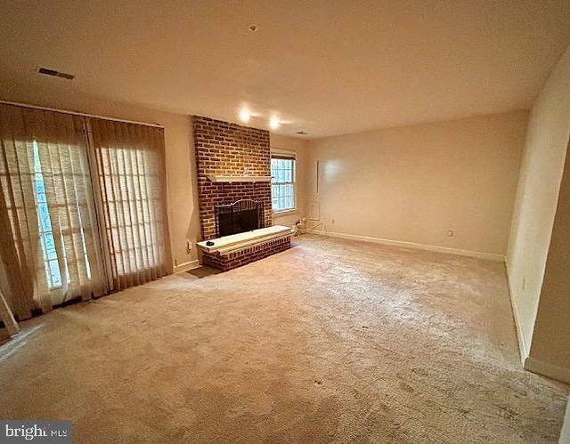 unfurnished living room with carpet flooring and a brick fireplace