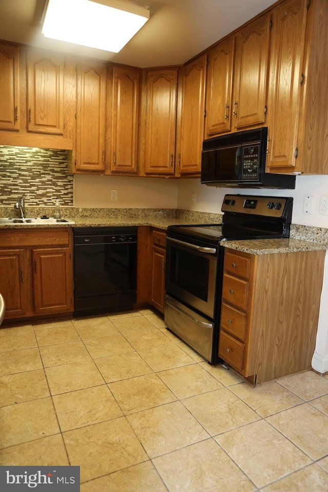 kitchen with sink, light tile patterned floors, stone counters, backsplash, and black appliances