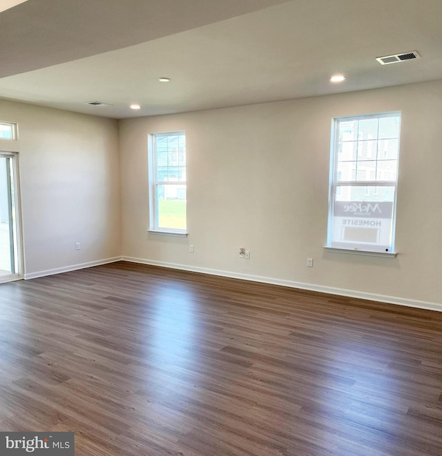 empty room with dark hardwood / wood-style floors and a healthy amount of sunlight