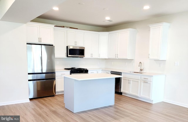 kitchen with appliances with stainless steel finishes, sink, white cabinetry, and a kitchen island