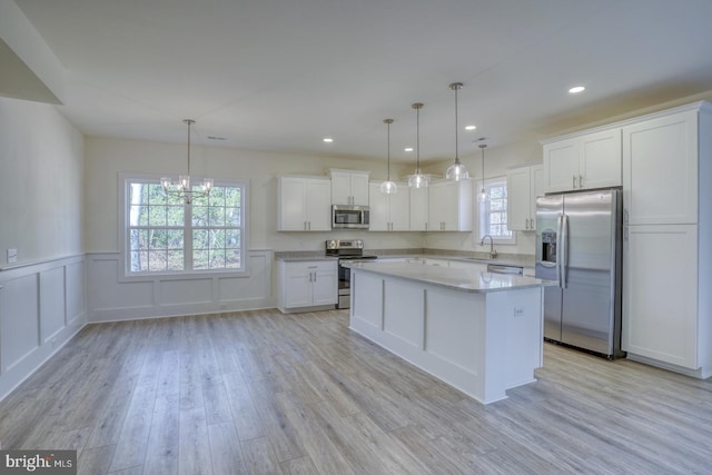 kitchen featuring white cabinetry, a center island, stainless steel appliances, and decorative light fixtures