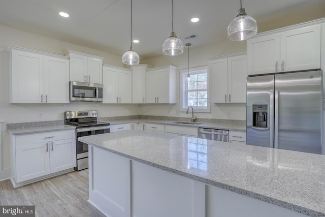 kitchen with decorative light fixtures, light stone countertops, white cabinetry, and stainless steel appliances