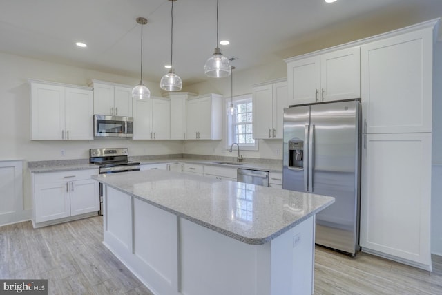 kitchen with white cabinets, appliances with stainless steel finishes, light stone countertops, and sink