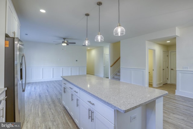 kitchen with stainless steel refrigerator with ice dispenser, ceiling fan, pendant lighting, white cabinets, and a center island