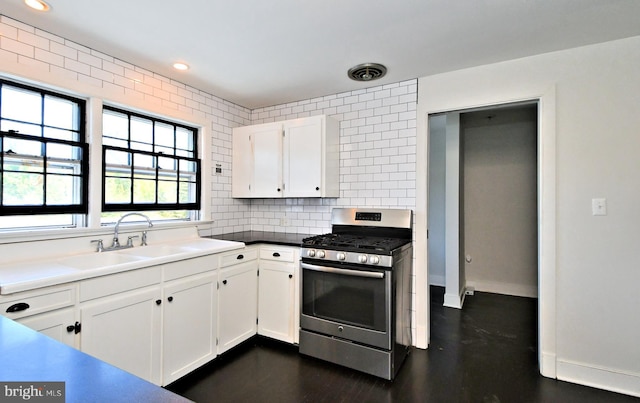 kitchen with decorative backsplash, sink, gas stove, and white cabinetry