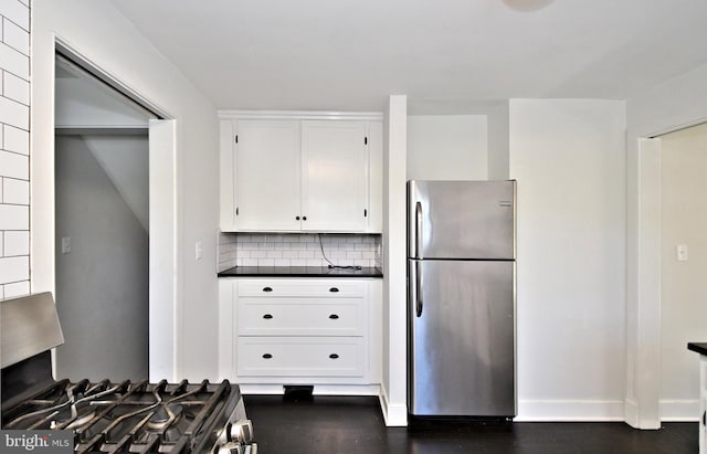 kitchen with dark wood-type flooring, stainless steel appliances, white cabinetry, and tasteful backsplash