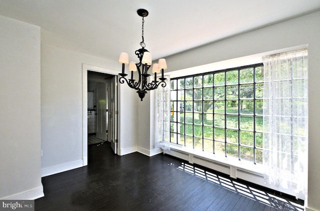 unfurnished dining area with a chandelier and dark hardwood / wood-style flooring