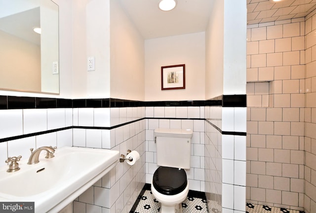 bathroom with toilet, tile walls, sink, and tile patterned flooring