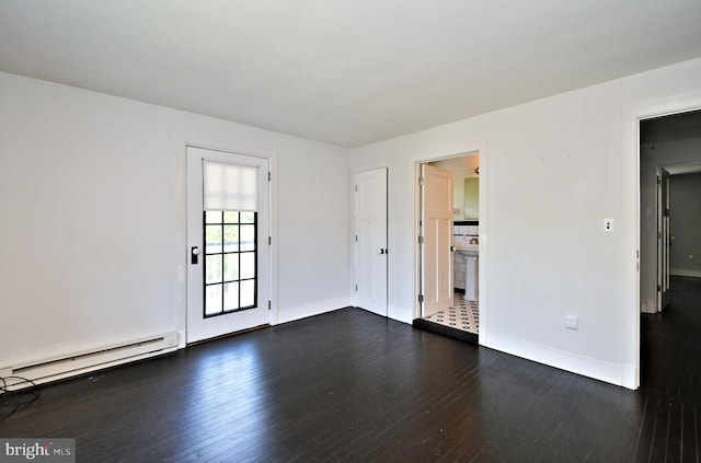 empty room featuring a baseboard heating unit and dark hardwood / wood-style flooring