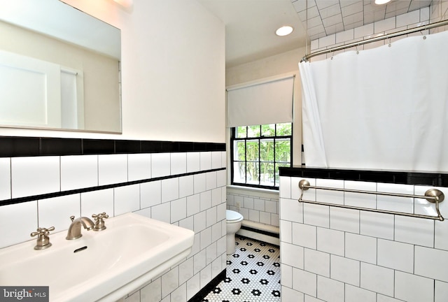 bathroom with tile patterned flooring, sink, tile walls, toilet, and walk in shower