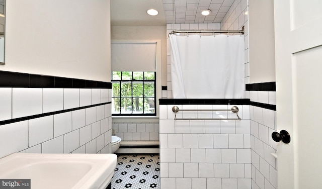 bathroom featuring toilet, a shower with curtain, tile walls, and tile patterned floors