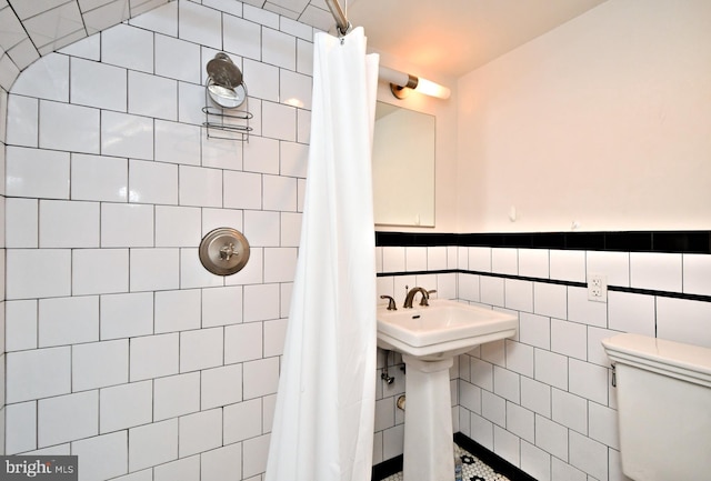 bathroom with toilet, tile walls, sink, and a shower with shower curtain