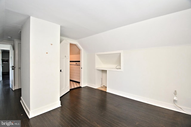 additional living space with dark hardwood / wood-style floors and vaulted ceiling