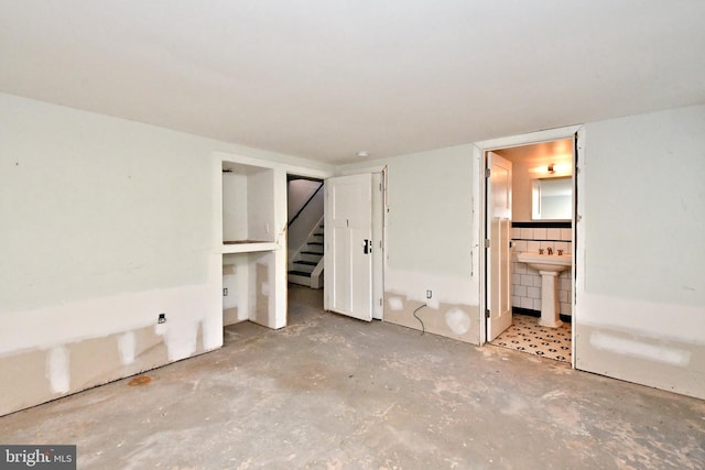 unfurnished bedroom featuring concrete floors, sink, and ensuite bathroom