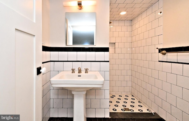 bathroom with a tile shower and tile walls