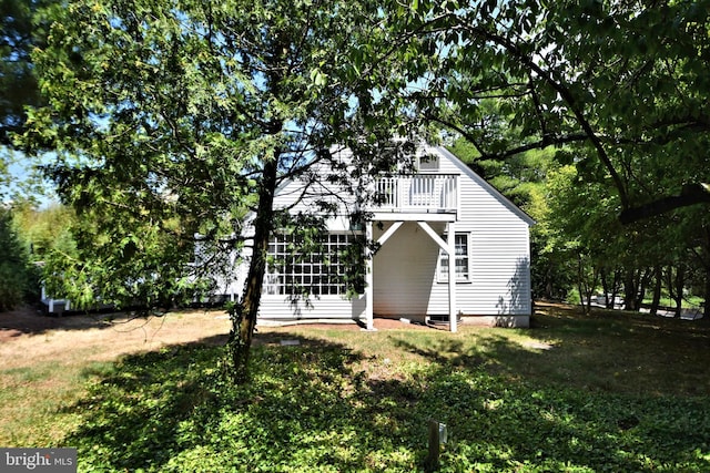 view of side of home with a lawn and a balcony