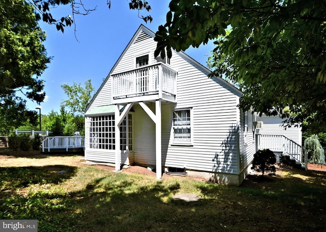 rear view of property with a wooden deck, a sunroom, and a lawn