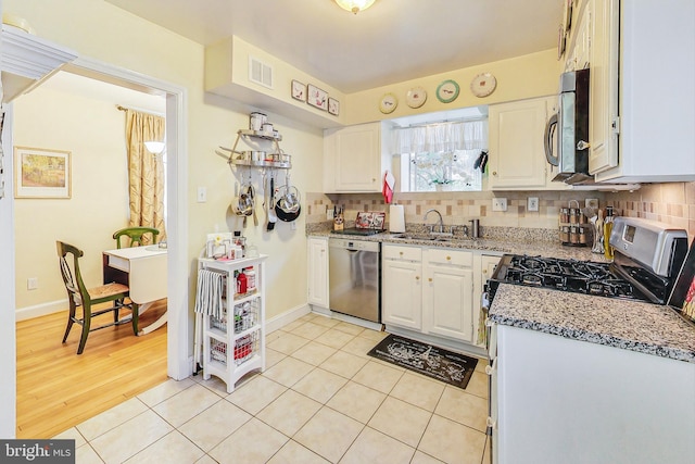 kitchen featuring light stone counters, sink, white cabinetry, and stainless steel appliances