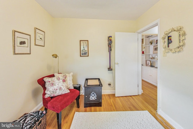 sitting room featuring wood-type flooring and built in shelves