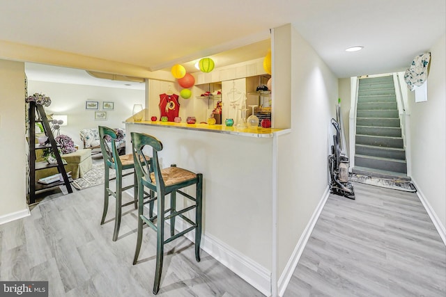 bar with light brown cabinetry and light hardwood / wood-style flooring