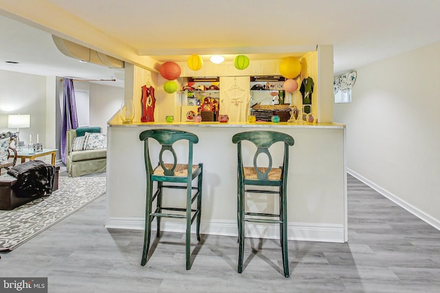 kitchen featuring hardwood / wood-style flooring, kitchen peninsula, and a breakfast bar