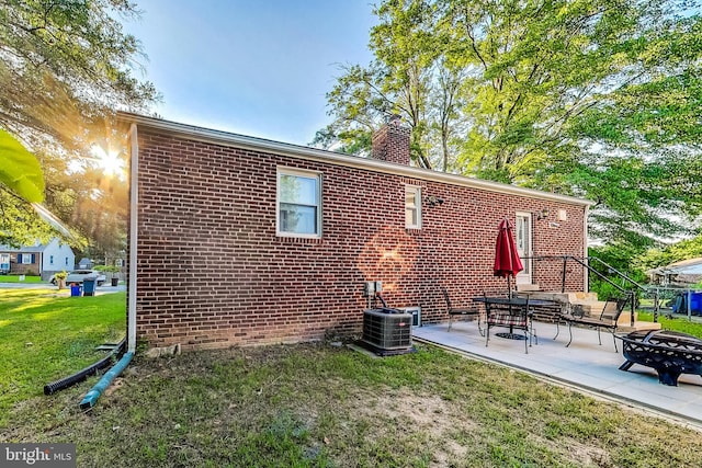 rear view of house featuring an outdoor fire pit, central AC unit, a lawn, and a patio