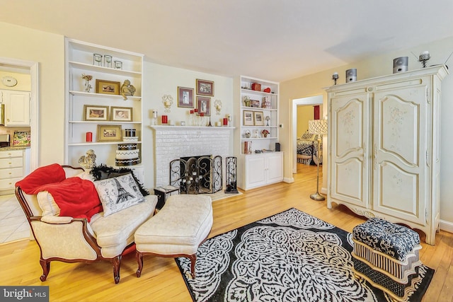 living room with light hardwood / wood-style floors, built in features, and a fireplace