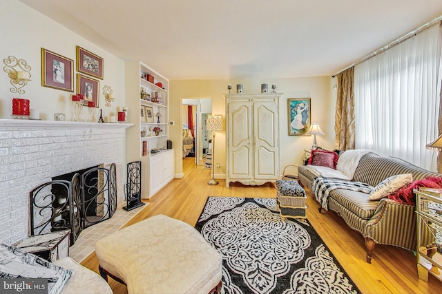 living room featuring a fireplace, light wood-type flooring, and built in features