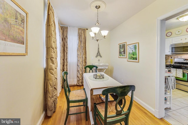 dining room with light wood-type flooring and a notable chandelier