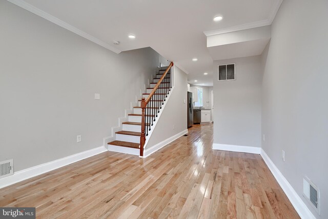 stairs featuring crown molding and light hardwood / wood-style flooring