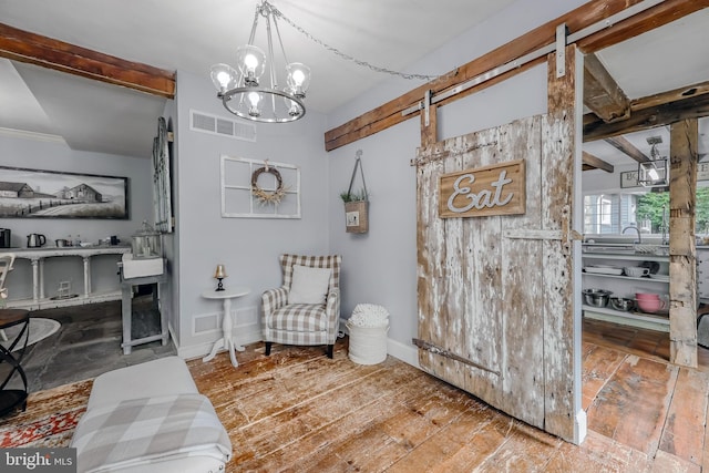 sitting room featuring wood-type flooring, a barn door, and a notable chandelier