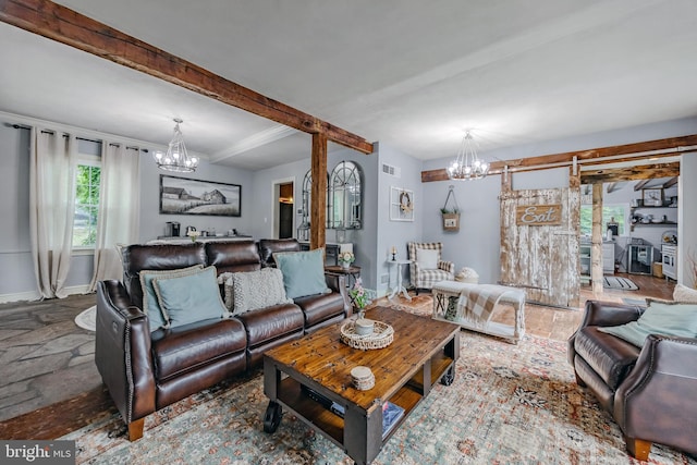 living room featuring beamed ceiling, a barn door, and a notable chandelier