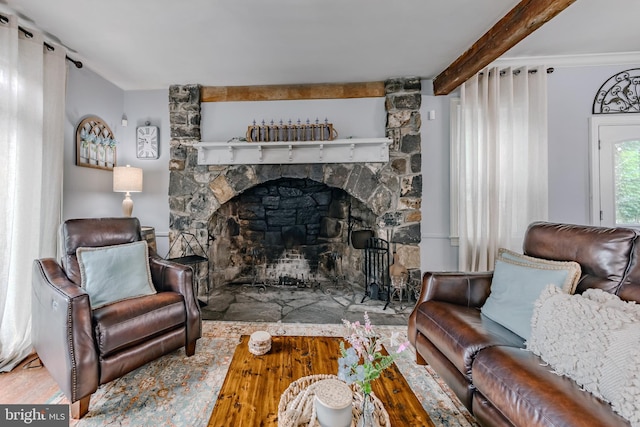 living room with crown molding, a stone fireplace, and hardwood / wood-style floors